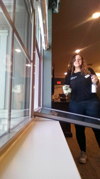 An employee standing by and opening the window about to clean the glass.