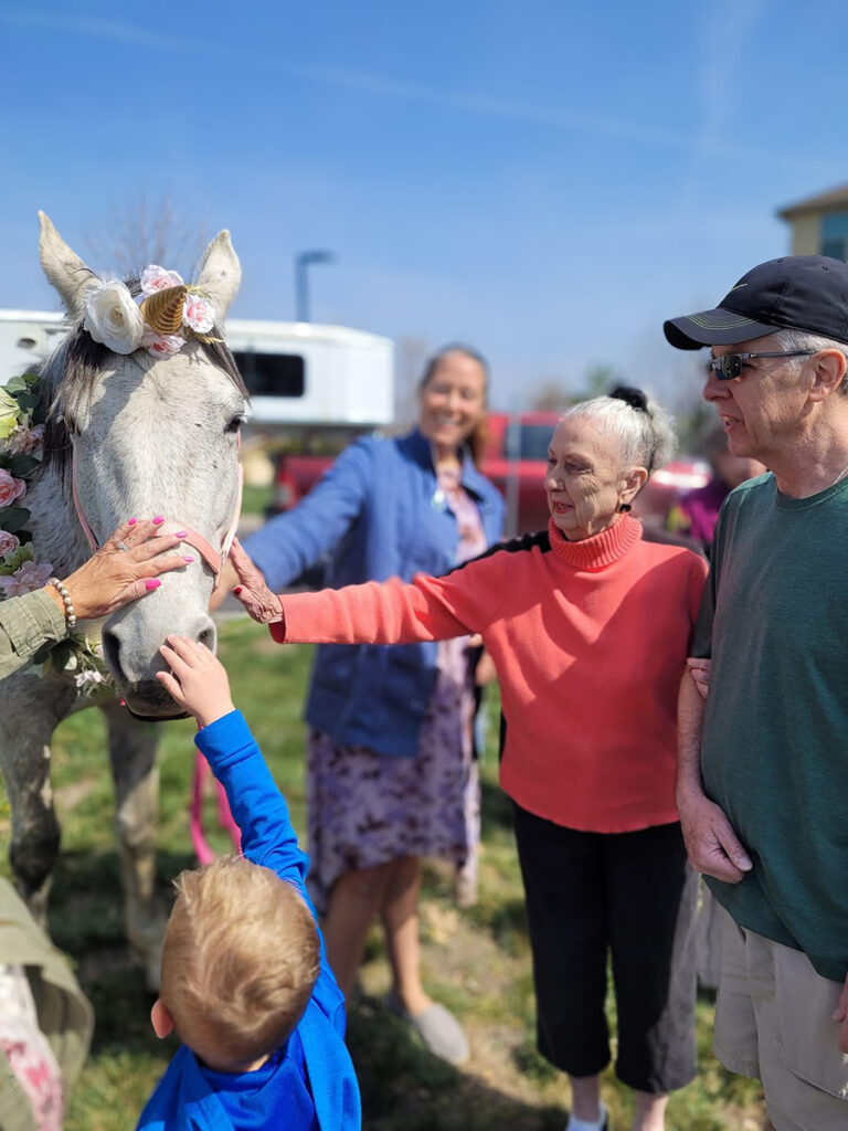 This was a community event at which residents, family, and children petted a "unicorn" with flowers along her mane.