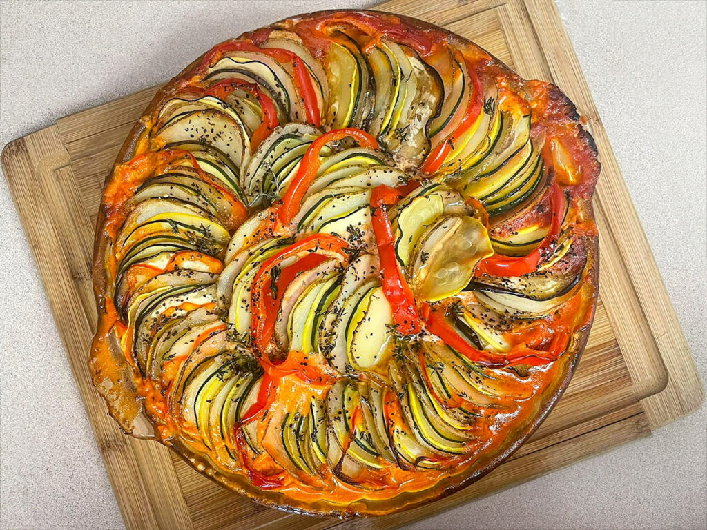 Vibrant Ratatouille made with tomatoes, zucchini, eggplant, and bell peppers, garnished with fresh herbs.