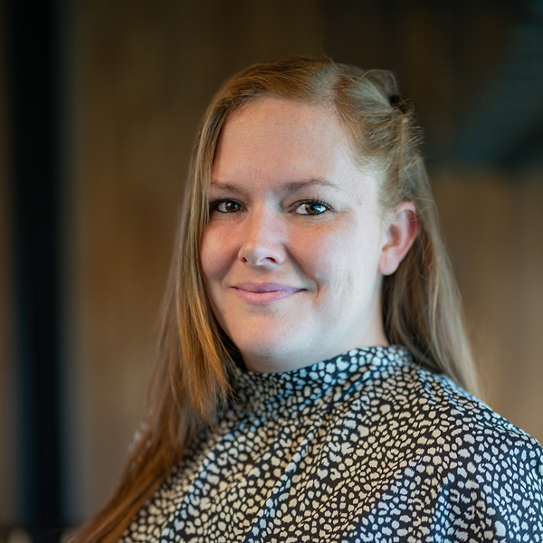 Emily Koziatek, Memory Care Director at The Westbury Senior Living, smiles in a patterned high-neck blouse against a softly lit indoor background.