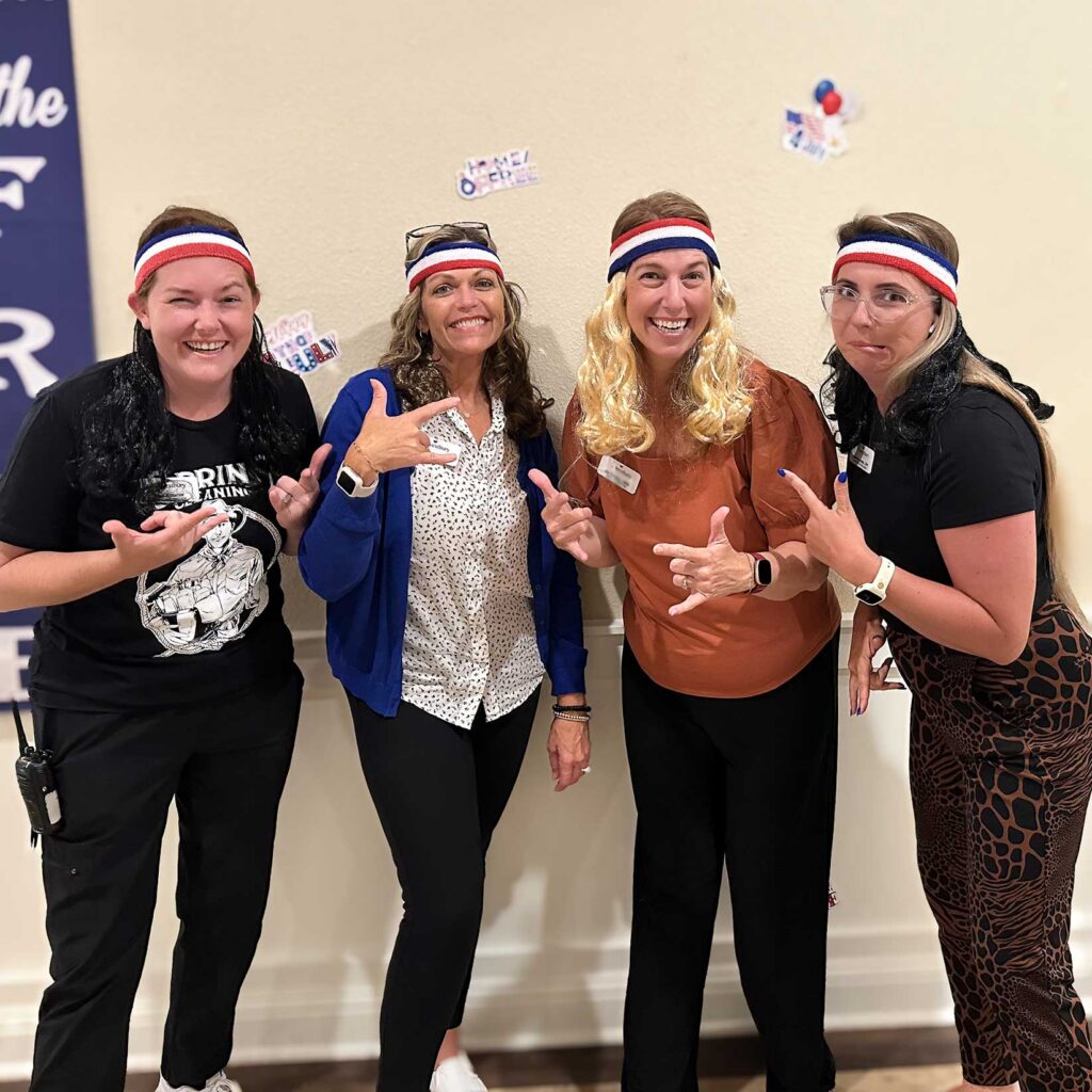 Four women on the team smile widely, wearing red, white, and blue headbands, during a patriotic event.
