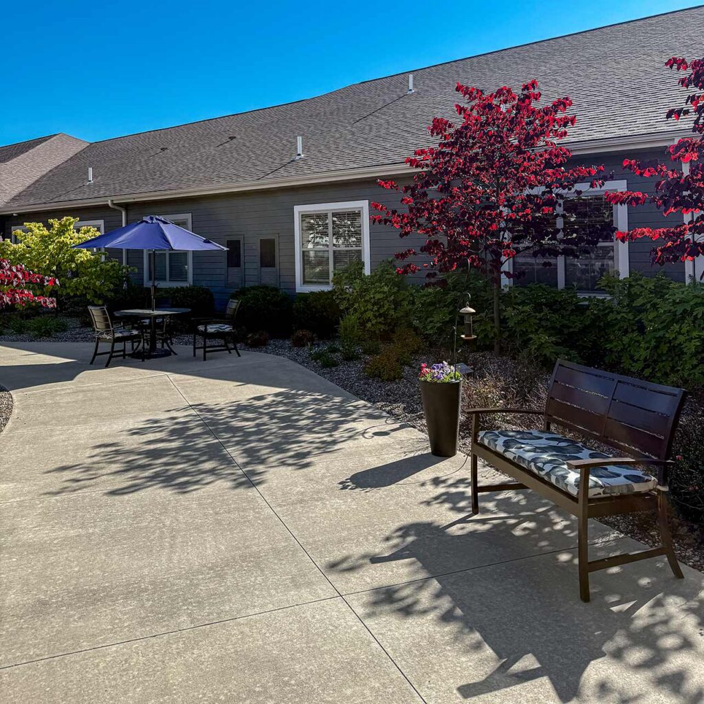 The courtyard at The Westbury Senior Living, featuring seating and trees of many varieties and colors.